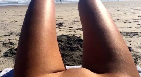 junge Nudistin sonnt sich nackt am FKK Strand
