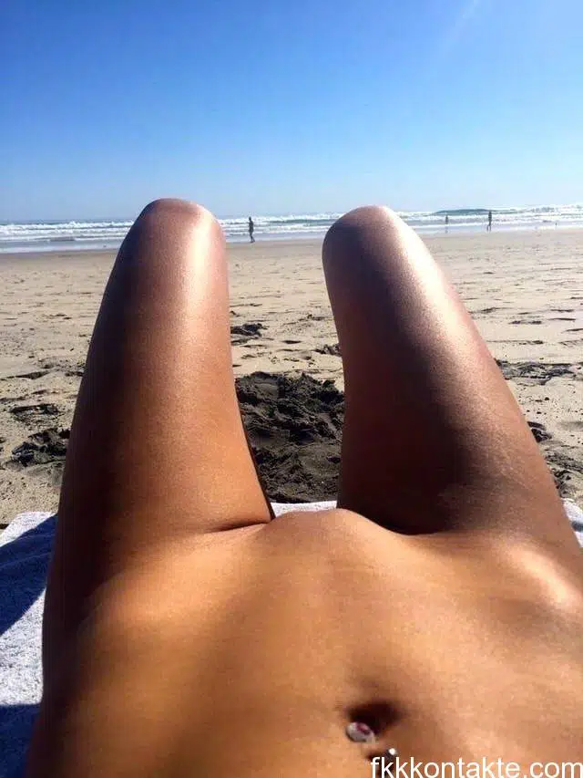 junge Nudistin sonnt sich nackt am FKK Strand